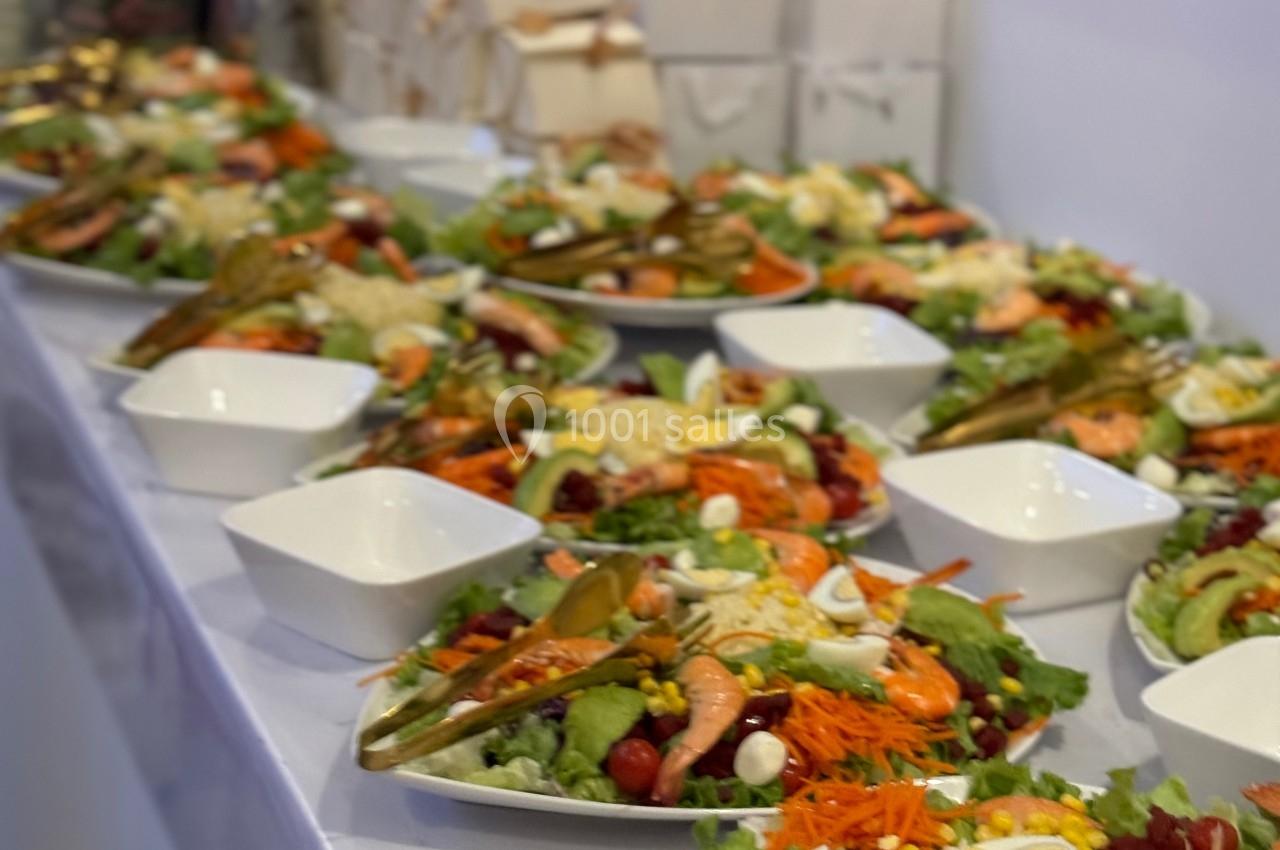 Assiettes de salades composées colorées alignées sur une table, accompagnées de bols et de sacs en arrière-plan.
