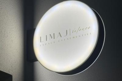 Un olivier taillé dans un grand bac blanc devant une façade moderne éclairée.