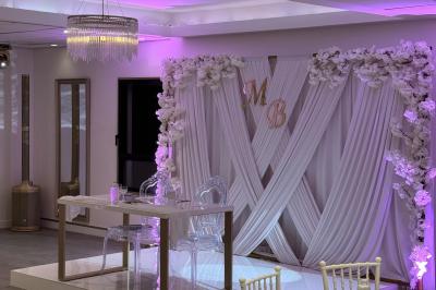 Un olivier taillé dans un grand bac blanc devant une façade moderne éclairée.