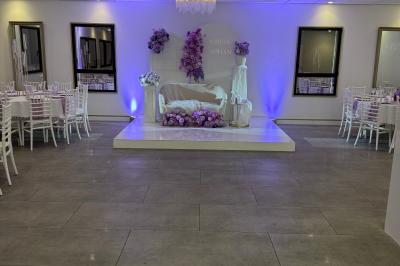 Un olivier taillé dans un grand bac blanc devant une façade moderne éclairée.