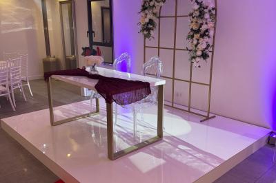 Un olivier taillé dans un grand bac blanc devant une façade moderne éclairée.