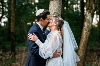 Un couple en tenue de mariage pose dans une forêt verdoyante, éclairée par une lumière douce.