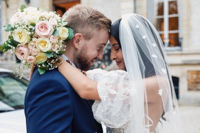 Un couple en tenue de mariage pose dans une forêt verdoyante, éclairée par une lumière douce.