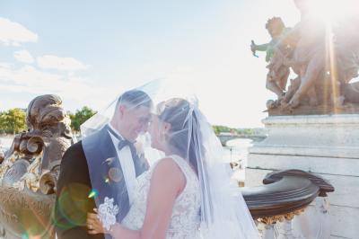 Un couple en tenue de mariage pose dans une forêt verdoyante, éclairée par une lumière douce.
