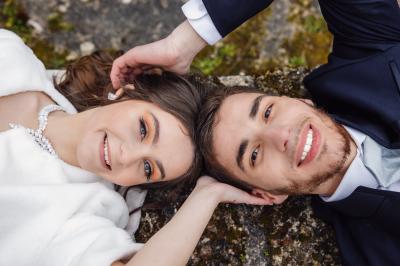 Un couple en tenue de mariage pose dans une forêt verdoyante, éclairée par une lumière douce.