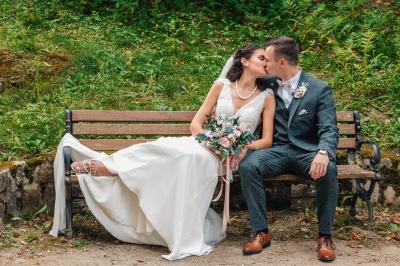 Un couple en tenue de mariage pose dans une forêt verdoyante, éclairée par une lumière douce.