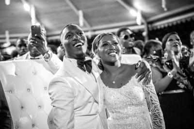 Un couple en tenue de mariage pose dans une forêt verdoyante, éclairée par une lumière douce.