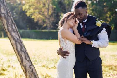 Un couple en tenue de mariage pose dans une forêt verdoyante, éclairée par une lumière douce.