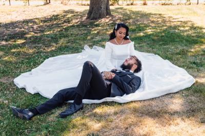 Un couple en tenue de mariage pose dans une forêt verdoyante, éclairée par une lumière douce.