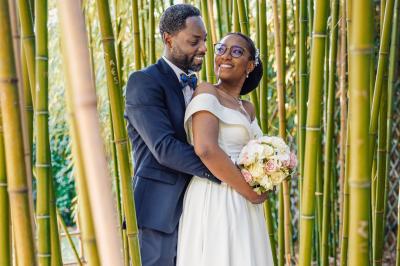 Un couple en tenue de mariage pose dans une forêt verdoyante, éclairée par une lumière douce.