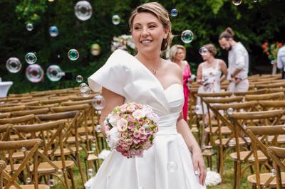 Un couple en tenue de mariage pose dans une forêt verdoyante, éclairée par une lumière douce.