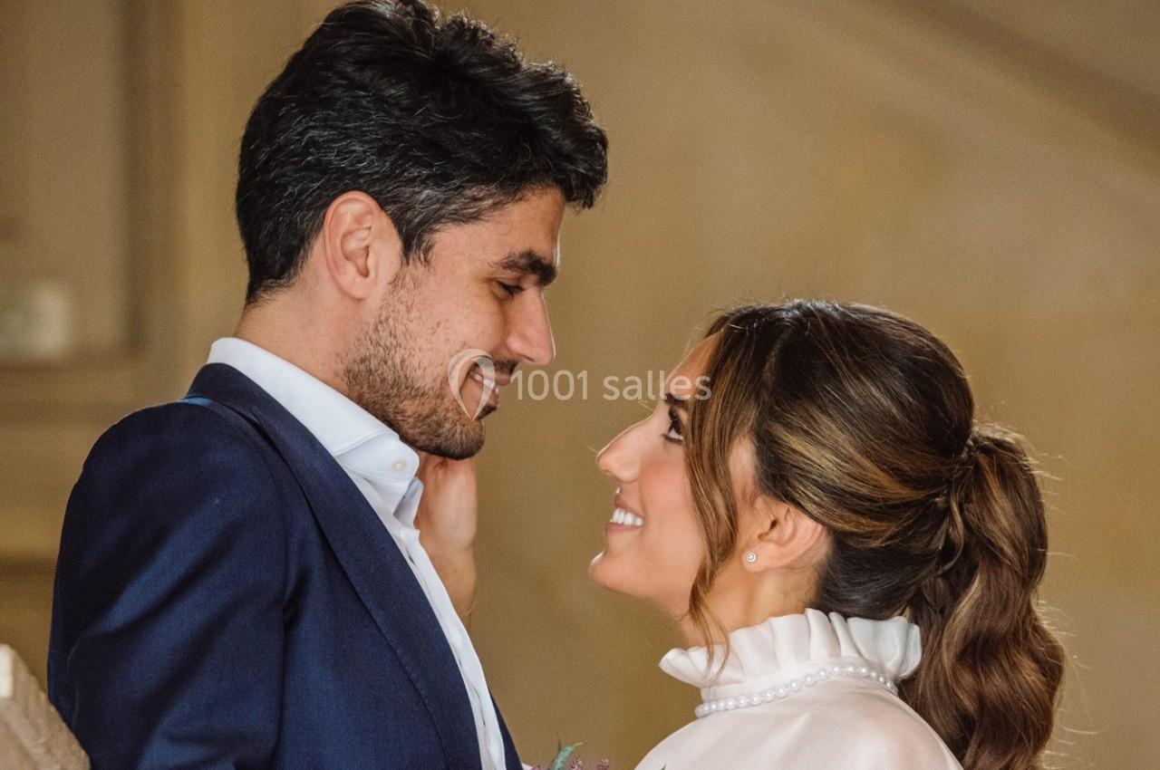 Un couple souriant se regarde avec tendresse dans un décor intérieur chaleureux.