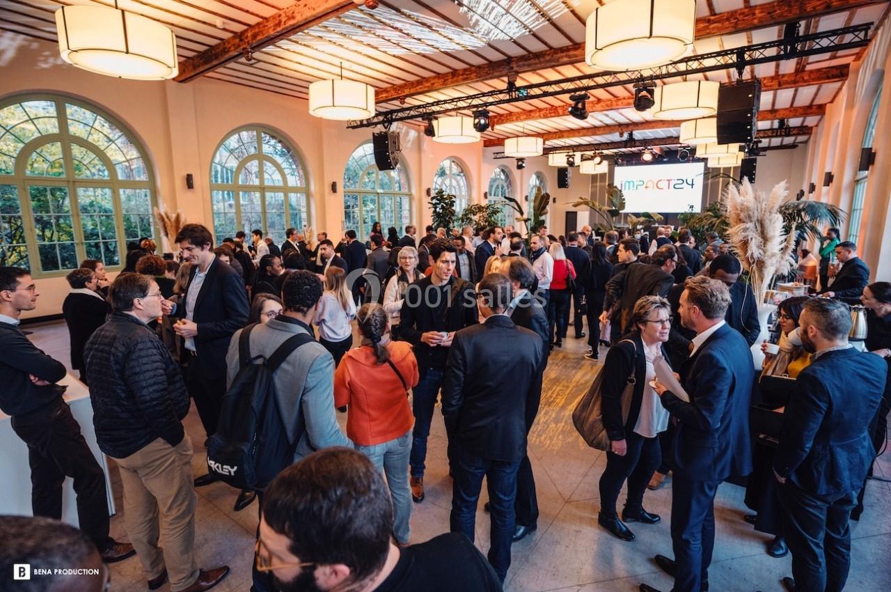 Groupe de personnes échangeant lors d'un événement professionnel dans une salle lumineuse avec de grandes fenêtres.