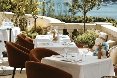 Un homme souriant partage un repas en terrasse, entouré de plats variés et d'une vue sur un paysage ensoleillé.