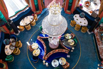Un homme souriant partage un repas en terrasse, entouré de plats variés et d'une vue sur un paysage ensoleillé.