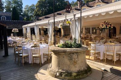 Salle de bain lumineuse avec miroirs, baignoire, serviettes orange et sol en carrelage rouge.
