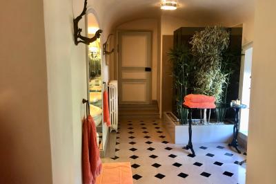 Salle de bain lumineuse avec miroirs, baignoire, serviettes orange et sol en carrelage rouge.