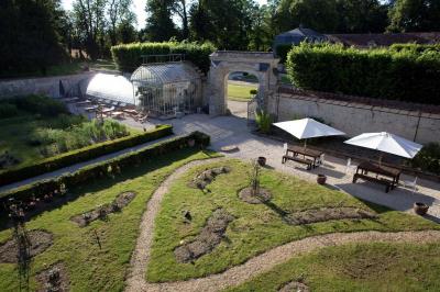 Salle de bain lumineuse avec miroirs, baignoire, serviettes orange et sol en carrelage rouge.