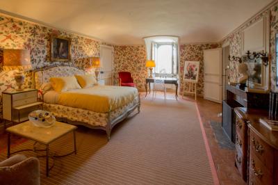 Salle de bain lumineuse avec miroirs, baignoire, serviettes orange et sol en carrelage rouge.