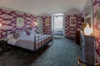 Salle de bain lumineuse avec miroirs, baignoire, serviettes orange et sol en carrelage rouge.