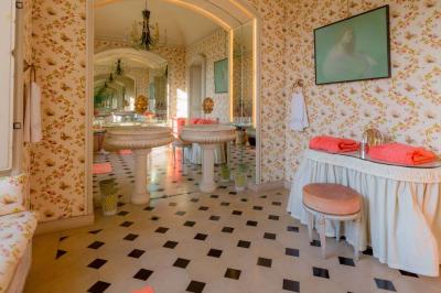 Salle de bain lumineuse avec miroirs, baignoire, serviettes orange et sol en carrelage rouge.