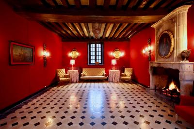Salle de bain lumineuse avec miroirs, baignoire, serviettes orange et sol en carrelage rouge.