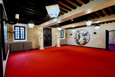 Salle de bain lumineuse avec miroirs, baignoire, serviettes orange et sol en carrelage rouge.