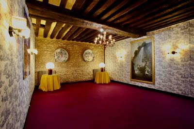 Salle de bain lumineuse avec miroirs, baignoire, serviettes orange et sol en carrelage rouge.