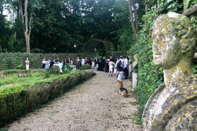 Salle de bain lumineuse avec baignoire, lavabo fleuri, miroirs, serviettes rouges et plafond peint en ciel nuageux.