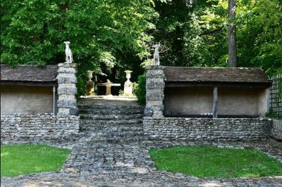 Salle de bain lumineuse avec baignoire, lavabo fleuri, miroirs, serviettes rouges et plafond peint en ciel nuageux.