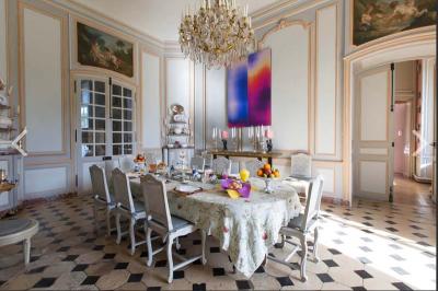 Salle de bain lumineuse avec baignoire, lavabo fleuri, miroirs, serviettes rouges et plafond peint en ciel nuageux.