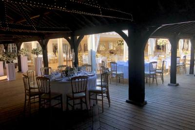Salle de bain lumineuse avec baignoire, lavabo fleuri, miroirs, serviettes rouges et plafond peint en ciel nuageux.
