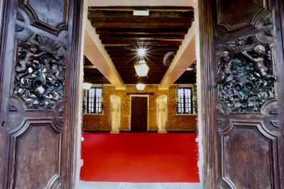 Salle de bain lumineuse avec baignoire, lavabo fleuri, miroirs, serviettes rouges et plafond peint en ciel nuageux.