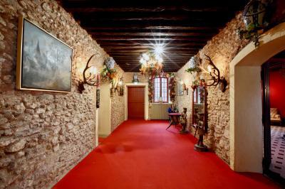 Salle de bain lumineuse avec baignoire, lavabo fleuri, miroirs, serviettes rouges et plafond peint en ciel nuageux.