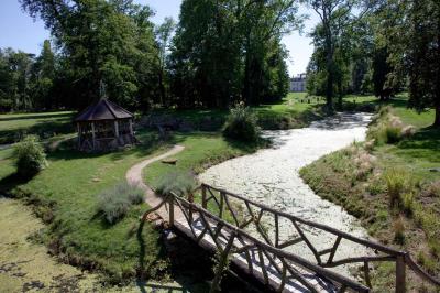 Salle de bain lumineuse avec baignoire, lavabo fleuri, miroirs, serviettes rouges et plafond peint en ciel nuageux.