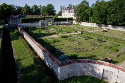 Salle de bain lumineuse avec baignoire, lavabo fleuri, miroirs, serviettes rouges et plafond peint en ciel nuageux.