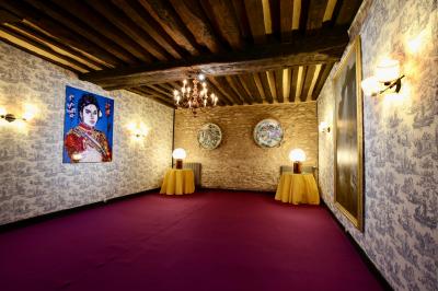 Salle de bain lumineuse avec baignoire, lavabo fleuri, miroirs, serviettes rouges et plafond peint en ciel nuageux.