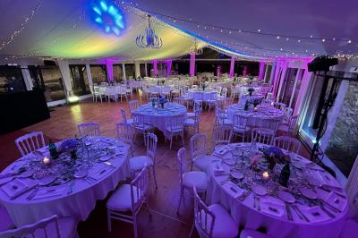 Salle de bain lumineuse avec baignoire, lavabo fleuri, miroirs, serviettes rouges et plafond peint en ciel nuageux.