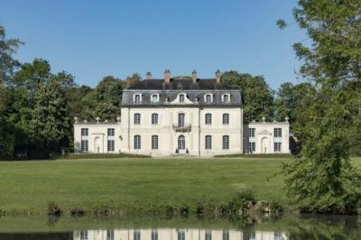 Salle de bain lumineuse avec baignoire, lavabo fleuri, miroirs, serviettes rouges et plafond peint en ciel nuageux.