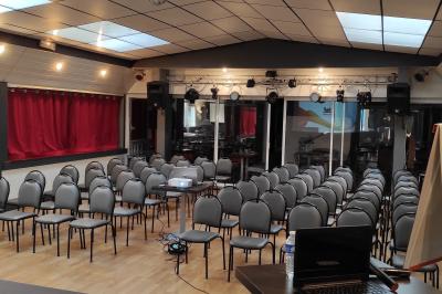 Viande en train de rôtir sur une broche au-dessus d'un barbecue en plein air, dans un jardin verdoyant.