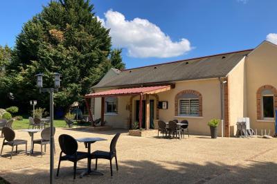 Viande en train de rôtir sur une broche au-dessus d'un barbecue en plein air, dans un jardin verdoyant.