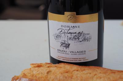 Bouteille de vin rouge Domaine Delaunay Anjou-Villages posée sur une table avec un morceau de pain au premier plan.