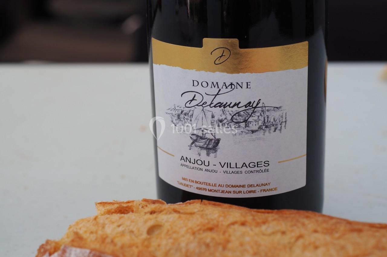 Bouteille de vin rouge Domaine Delaunay Anjou-Villages posée sur une table avec un morceau de pain au premier plan.