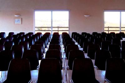 Vue d'un paysage rural avec un bâtiment moderne à gauche, des vignes et un château au loin sous un ciel dégagé.