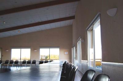 Vue d'un paysage rural avec un bâtiment moderne à gauche, des vignes et un château au loin sous un ciel dégagé.