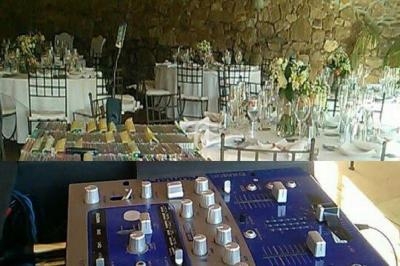 Table de mixage et microphone au premier plan, avec une salle de réception décorée et des tables dressées en arrière-plan.