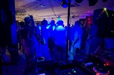 Console de mixage DJ avec éclairage coloré en arrière-plan dans un environnement intérieur.