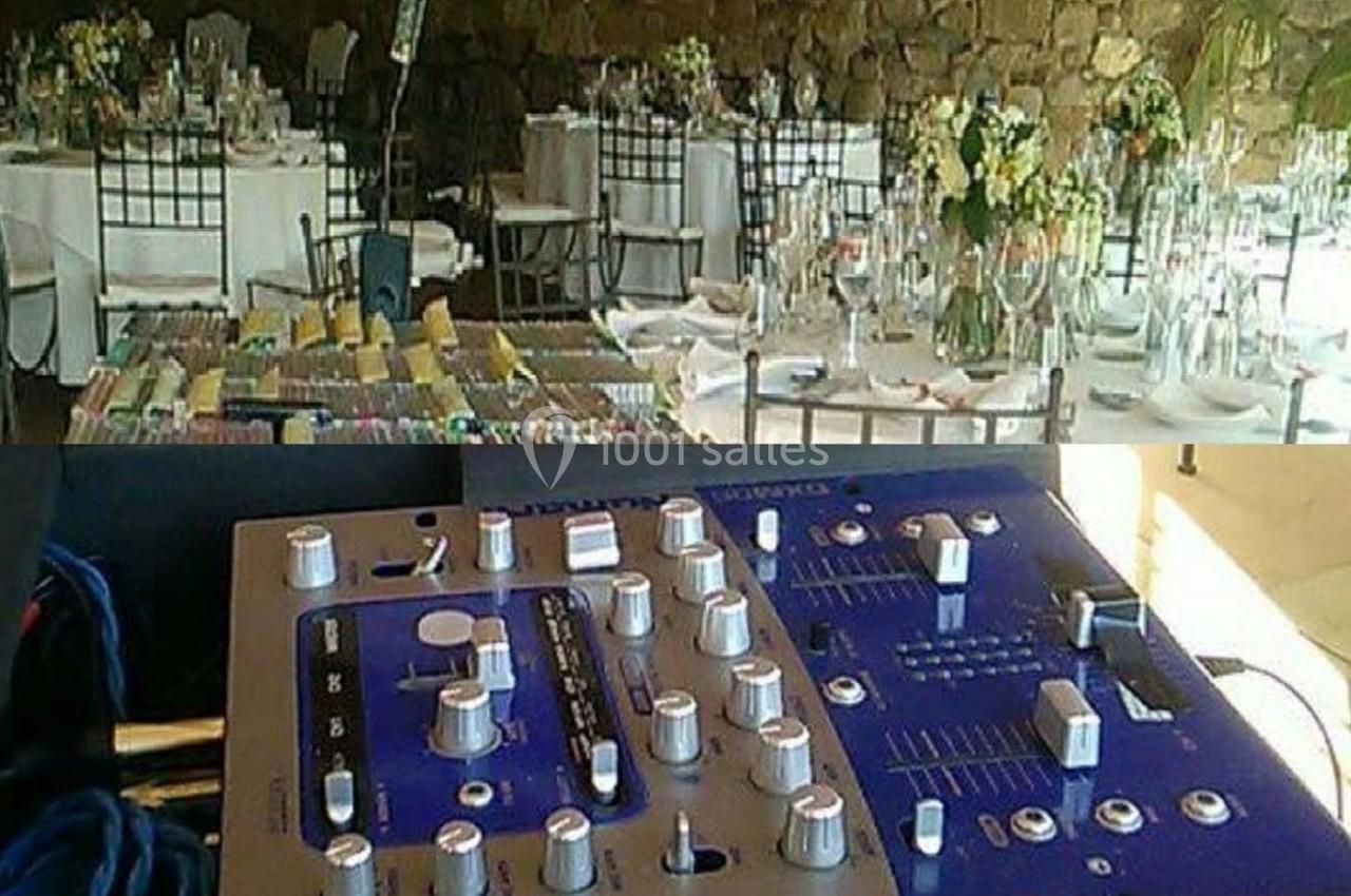 Salle de réception décorée avec des tables dressées et un équipement de mixage audio au premier plan.