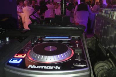 Console de mixage DJ avec éclairage coloré en arrière-plan dans un environnement intérieur.