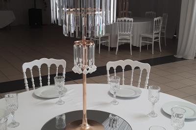 Centre de table élégant avec des roses blanches et des pampilles en cristal, entouré de vaisselle sur une nappe blanche.